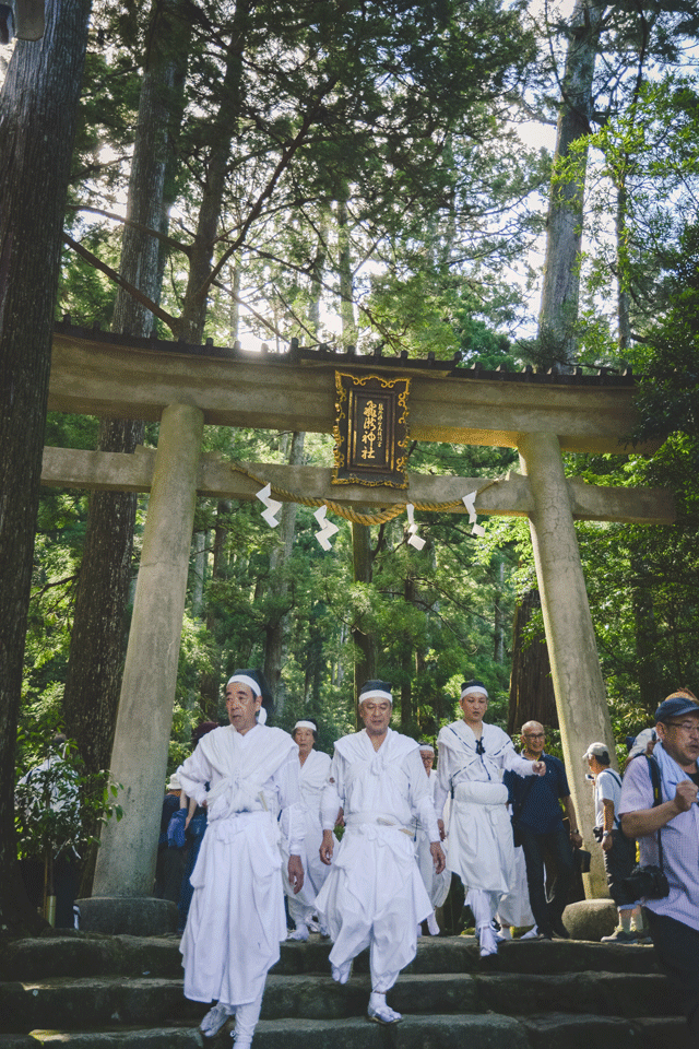Volunteers and those receiving training pass through the Tori Gate of Hiro Shrine, ready to retire at the top of the mountain. Throughout the day they were cheered on, and celebrated as local heroes. Many visitors clamored for photos and souvenirs from the fire-bearers, asking for fans and pieces of the burned torches. Greatly humored and in good spirits, the men then made the long trek back up the trail, to be in peace until next year.
