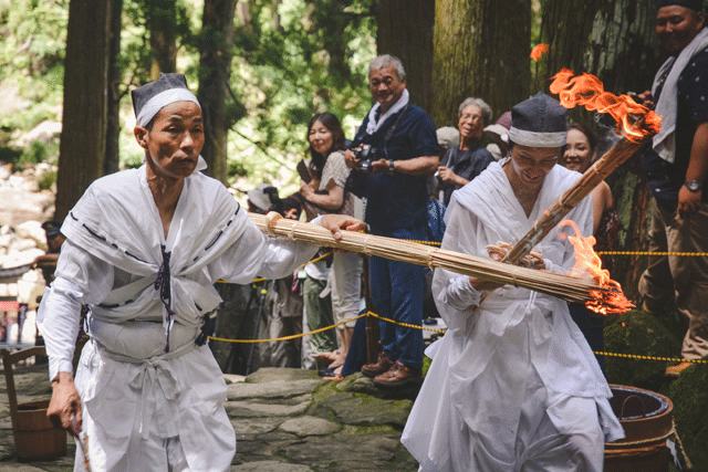 The two men from the top of the mountain have made their way to the shrine, and met a priest at the bottom. After receiving a blessing at the bottom of Nachi Taki, they make their way back up, to meet and light the fires of the other torches. The fire will help drive away the evils and misfortunes for the coming year, and offer protection for the blessings and gods dwelling in the mountains.