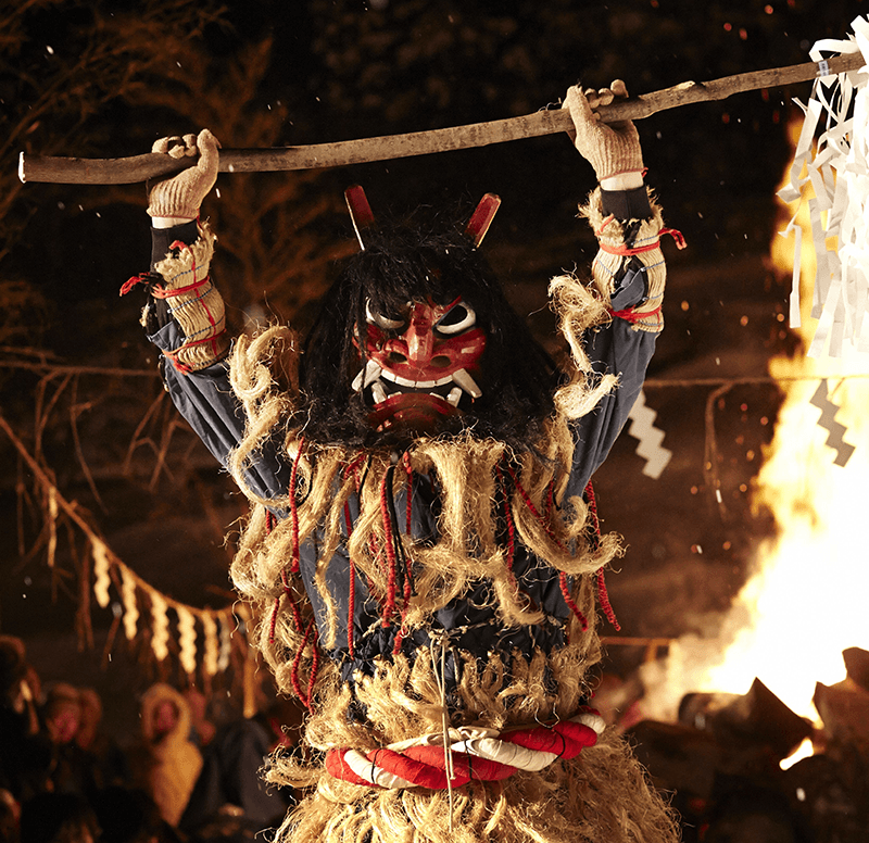 a man in a namahage costume holds up a staff