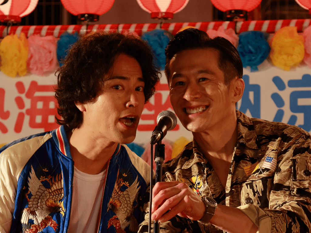 still from the movie hibana showing two comedians standing in front of the microphone