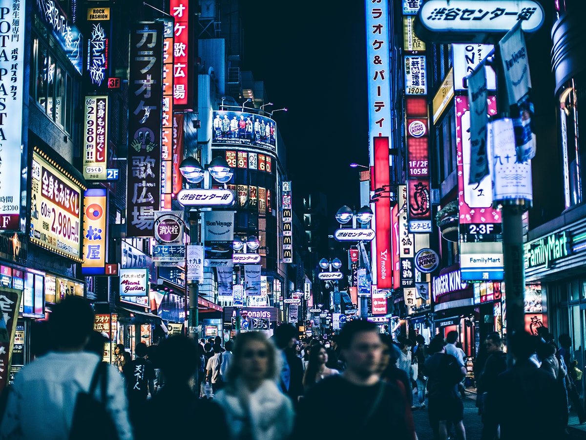 scene of a crowd in Shibuya Tokyo with neon signs