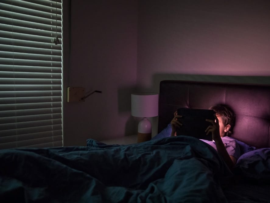 a child plays on his ipad in his darkened bedroom