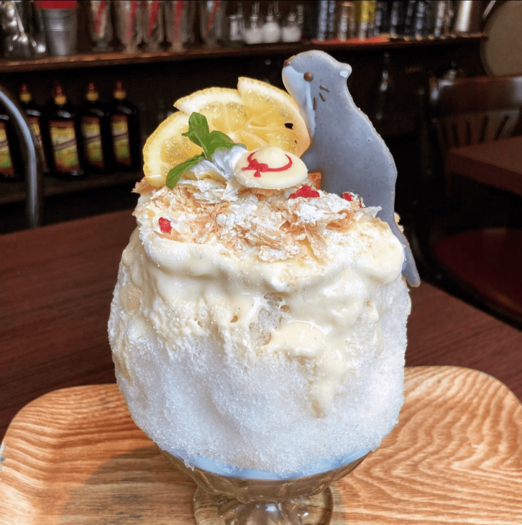 cute otter biscuit on top mound of white shaved ice along with hedgehog made of cute lemon
