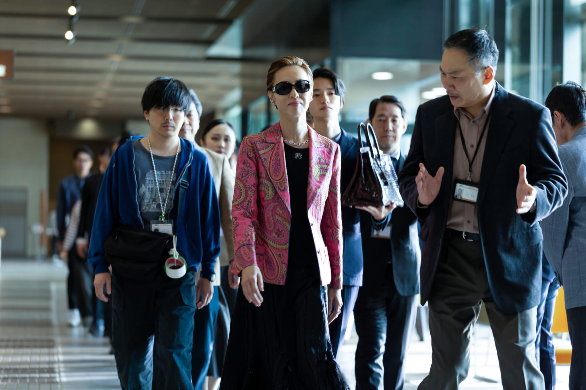 Kazuko Hosoki walking while surrounded by her production team