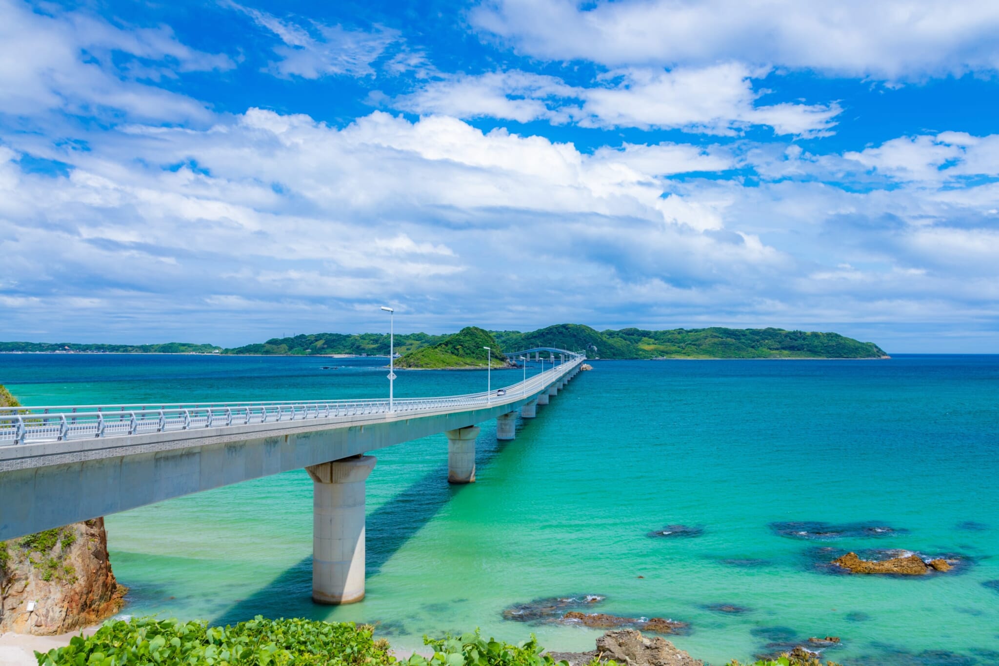 Aerial view of Tsunoshima Bridge crossing emerald sea in Yamaguchi.